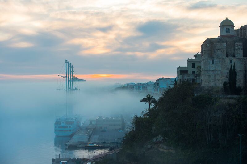 The mast of a sailboat rises above the fog that covers the port of Mahon, Balearic Islands, Spain. EPA