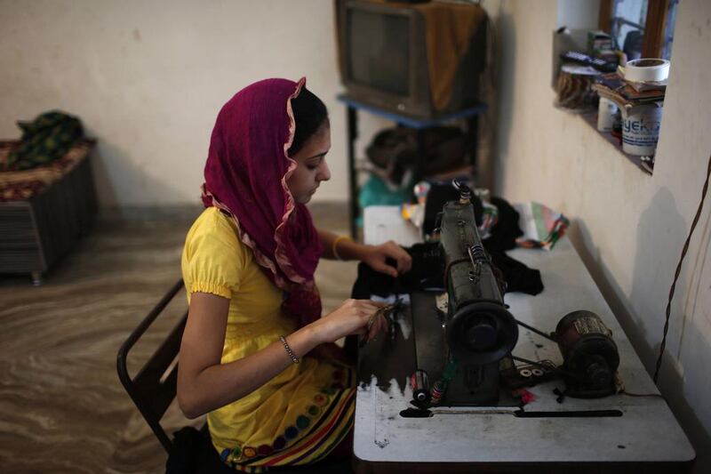 A Muslim girl uses a sewing machine in her house.