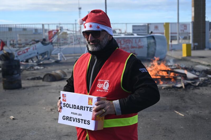 A CGT unionist holds a box for strike fund donations during a Christmas lunch on December 24, 2019 at the autonomous port of Marseille, on the 20th day of a nationwide multi-sector strike over French government's plan to overhaul the country's retirement system. / AFP / Christophe SIMON
