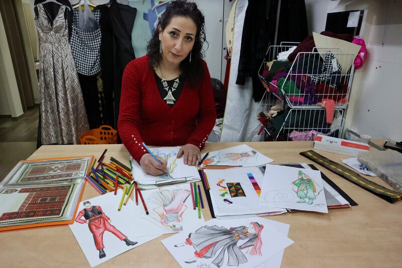Khawla al-Tawil sketches designs for traditional Palestinian outfits.