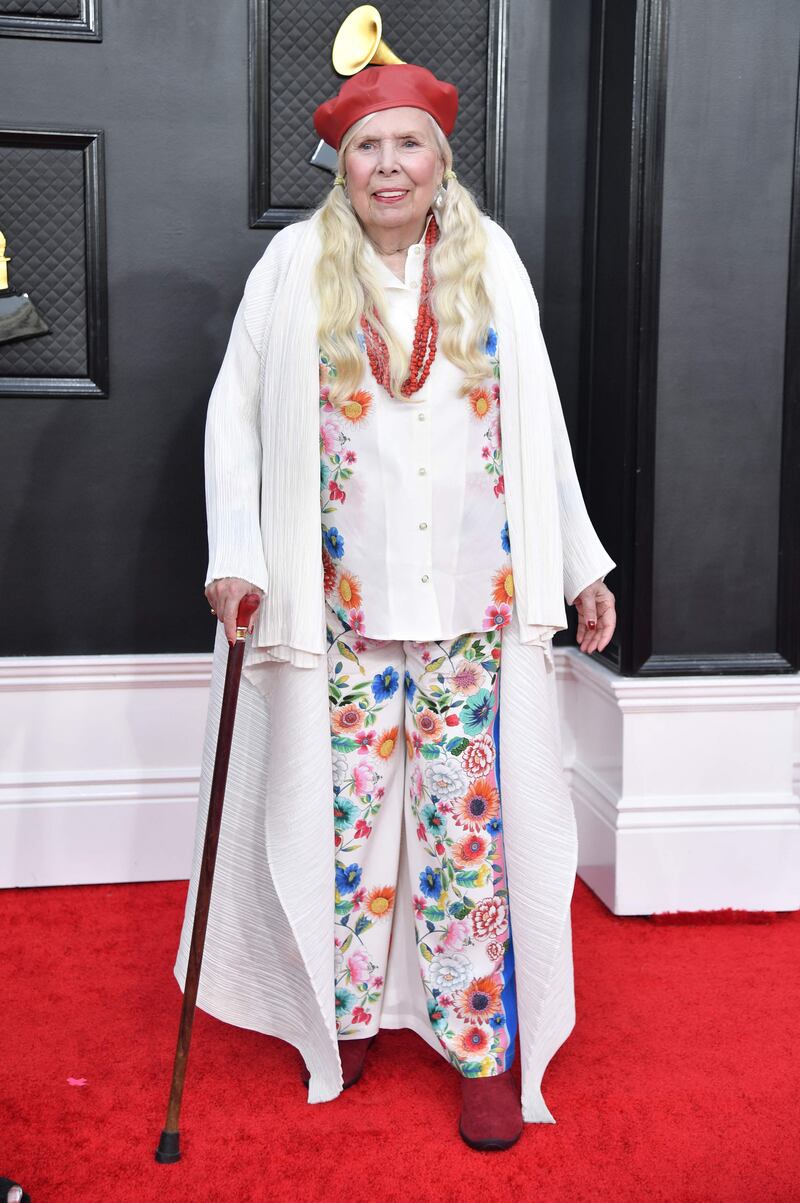 Joni Mitchell, wearing a floral top and trouser set with a red beret. AFP