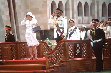 OMAN - FEBRUARY 28: The Queen With Sultan Qaboos In Oman. During The Arrival Ceremony At Sultan Qaboos' S Home Muscat Palace. She Is Holding Onto Her Hat After It Had Been Knocked Off By The Wind (day Date Not Certain. Gulf Tour Dates 12 Feb - 1 March 1979) (Photo by Tim Graham Photo Library via Getty Images)