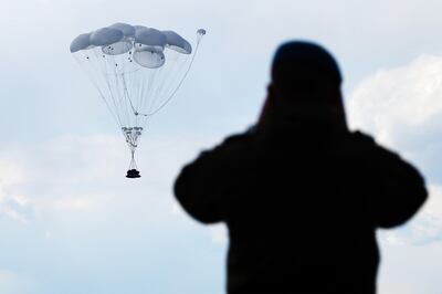 A Russian soldier looks on as a BMD-4M infantry vehicle strapped to parachutes descends after being dropped from a cargo plane in 2017. Alamy