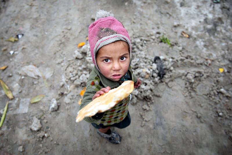 An Afghan child standing on the snow poses for a photograph at an Internal Displaced Persons (IDP) camp in Kabul.  EPA