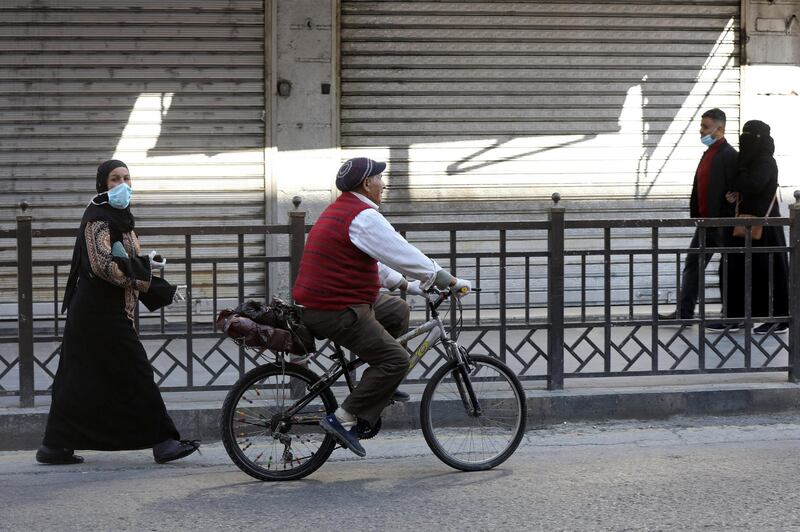 People wear personal protective equipment amid concerns over the coronavirus disease (COVID-19) as they walk next to closed shops in Amman, Jordan,  April 12, 2020. REUTERS/Muhammad Hamed