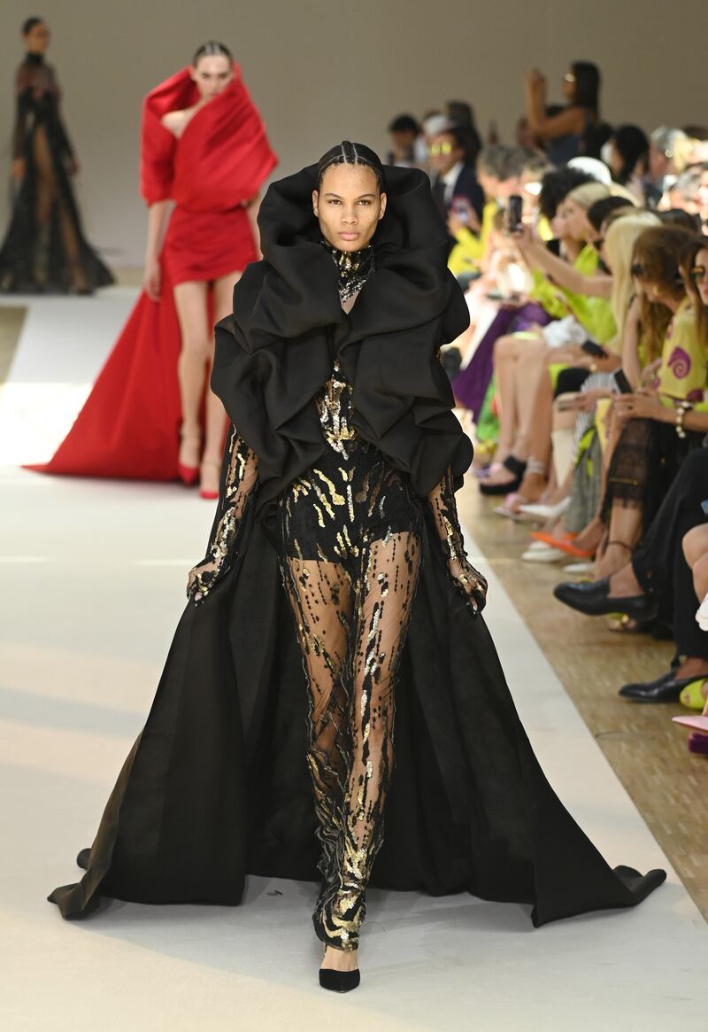 A sheer, beaded dress is covered with a dramatic cape. Getty
