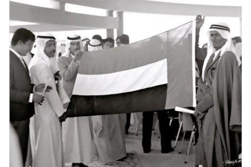 The flag of the United Arab Emirates is held up before being raised in Dubai and Abu Dhabi for the first time. Ramesh Shukla