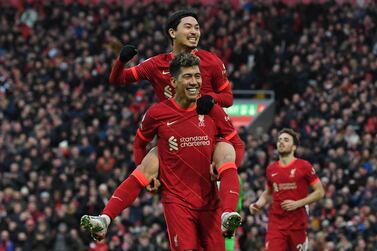 Liverpool's Japanese midfielder Takumi Minamino jumps on the back of Liverpool's Brazilian midfielder Roberto Firmino as he celebrates scoring his team's third goal during the English Premier League football match between Liverpool and Brentford at Anfield in Liverpool, north west England on January 16, 2022.  (Photo by Paul ELLIS / AFP) / RESTRICTED TO EDITORIAL USE.  No use with unauthorized audio, video, data, fixture lists, club/league logos or 'live' services.  Online in-match use limited to 120 images.  An additional 40 images may be used in extra time.  No video emulation.  Social media in-match use limited to 120 images.  An additional 40 images may be used in extra time.  No use in betting publications, games or single club/league/player publications.   /  