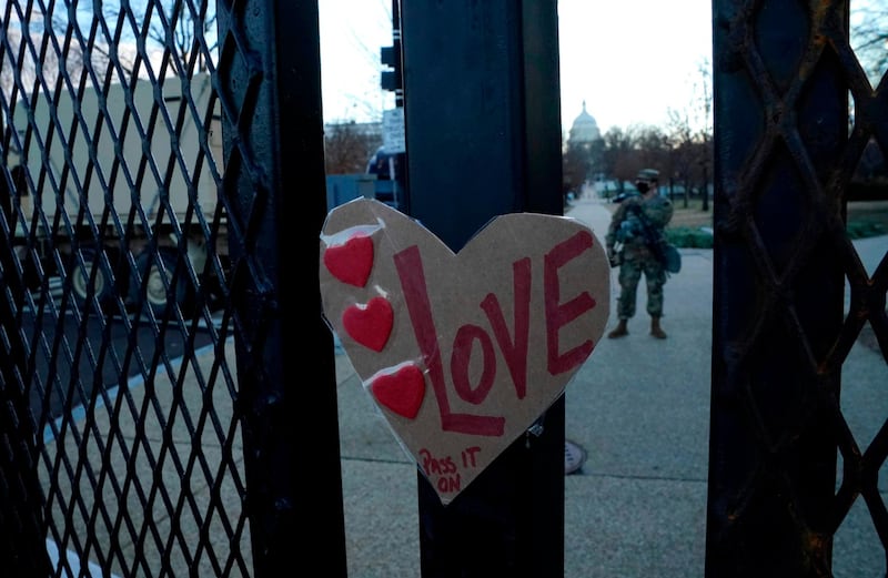 A sign reading 'Love' is placed on a barrier outside the US Capitol as National Guard troops stand guard. AFP