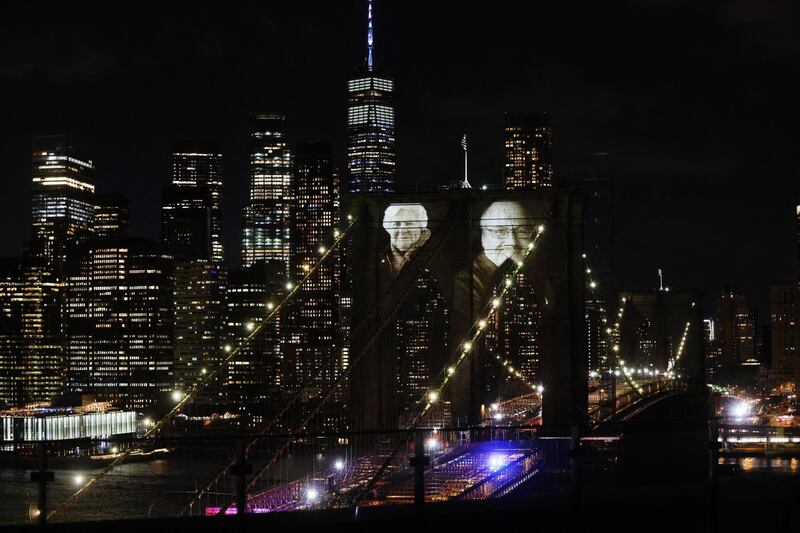 NEW YORK, NY - MARCH 14: Faces of victims of COVID-19 are projected onto the Brooklyn Bridge during a memorial service called â€œA COVID-19 Day of Remembranceâ€ on March 14, 2021 in New York City. The event, which will include a virtual performance by The New York Philharmonic, marks the day the first known coronavirus fatality was confirmed in the city.   Spencer Platt/Getty Images/AFP (Photo by SPENCER PLATT / GETTY IMAGES NORTH AMERICA / Getty Images via AFP)