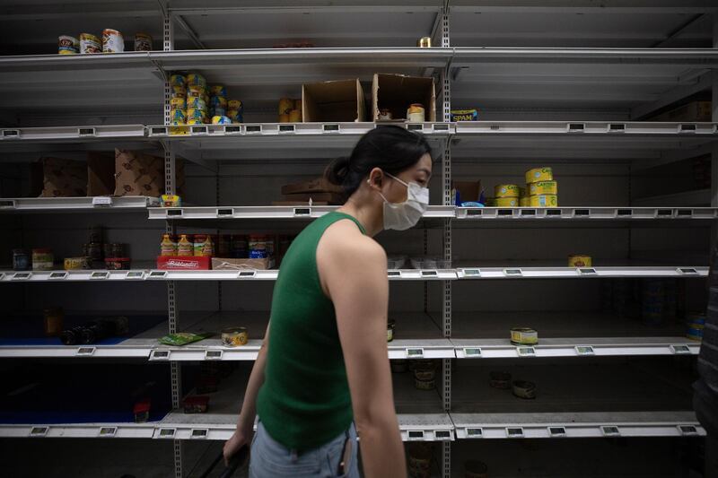 A customer walks by an almost empty shelf of canned food and instant noodles at a supermarket in Singapore.  EPA