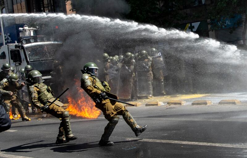A Molotov cocktail explodes in front of riot police during a protest in the framework of the Day of the Race, in downtown Santiago.  AFP