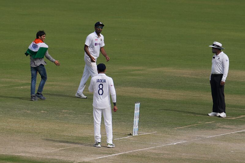 An Indian cricket fan, left, ran on to the pitch on the third day of the first Test in Mohali. AP