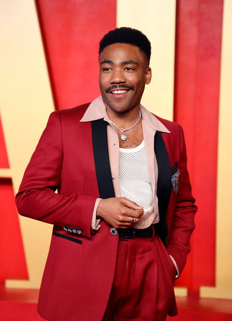 Donald Glover teams a T shirt and open shirt with his mulberry red tuxedo. AFP