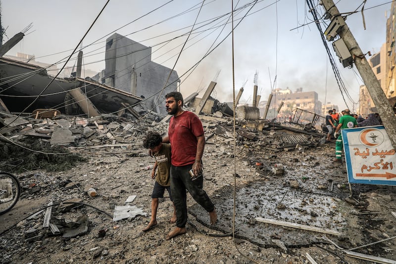 A Palestinian man and his son walk among the rubble of an area in Gaza city levelled in Israeli air strikes that have killed more than 6,500. EPA