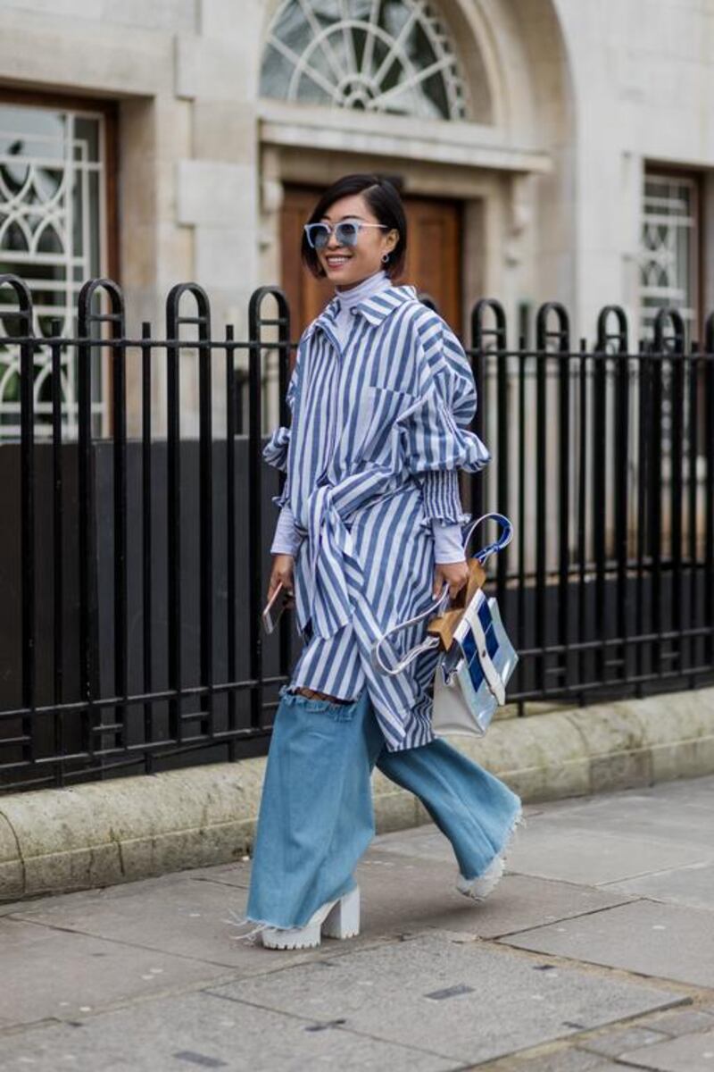 A guest wearing a blue white striped button shirt, ripped denim jeans outside Anya Hindmarch on day 3 of the London Fashion Week February 2017. Christian Vierig / Getty Images