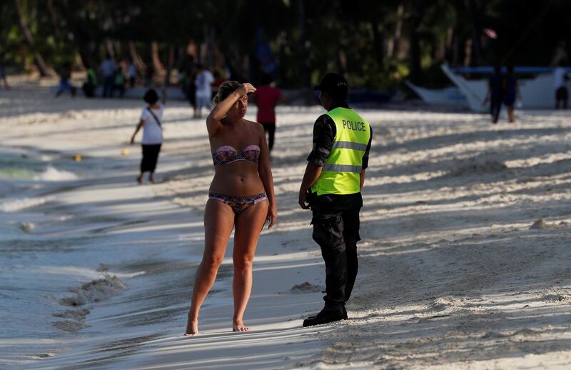 A policeman asks a tourist to leave the beach during the shutdown of the holiday island Boracay, in Philippines on April 26, 2018. Erik De Castro / Reuters