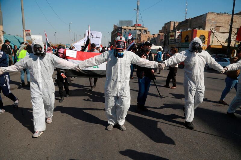 Anti-government protesters wear hazmat suits and gas masks during a protest to condemn the militia attack on Najaf protesters late on Wednesday night, in Tahrir Square, Baghdad, Iraq. AP Photo