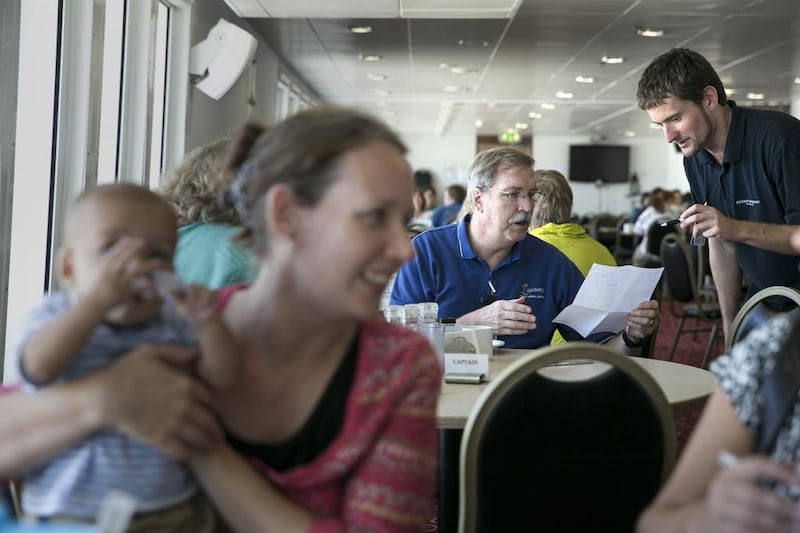 Carlien Govender sits with her son Milan, 8 months, while captain Tom Dyer, a 30-year veteran of the mission, talks with Sylvester Janik during a lunch at the Logos Hope ship's canteen. Silvia Razgova / The National
