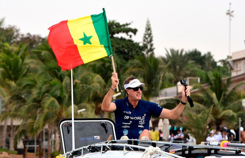 Patrick Bol, Dutch skipper of the Row4ocean rowing trimaran holds a Senegalese flag as his team leaves Dakar. AFP