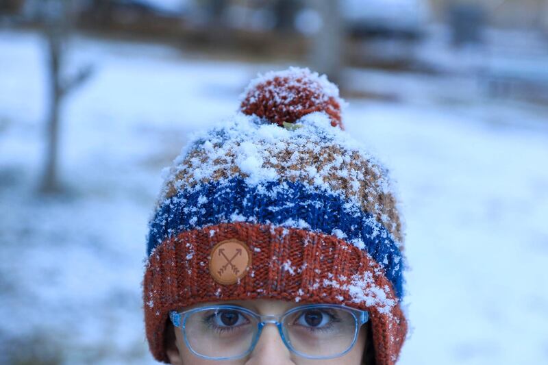 An Iraqi boy poses with his snow covered hat in the holy Shiite city of Karbala.  AFP