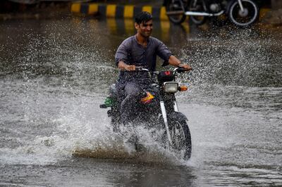 A motorcyclist makes his way through a flooded street after heavy rain in Karachi on Monday. AFP
