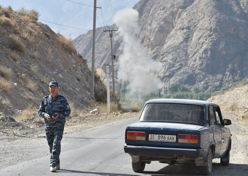 A police officer walks on a road as smoke rises after an explosion during a de-mining operation near the Kyrgyz-Tajik border in the village of Ak-Say, some 1000 kilometres from Bishkek, on September 21, as the worst violence the two ex-Soviet countries have seen in years broke out last week on their contested border.  AFP