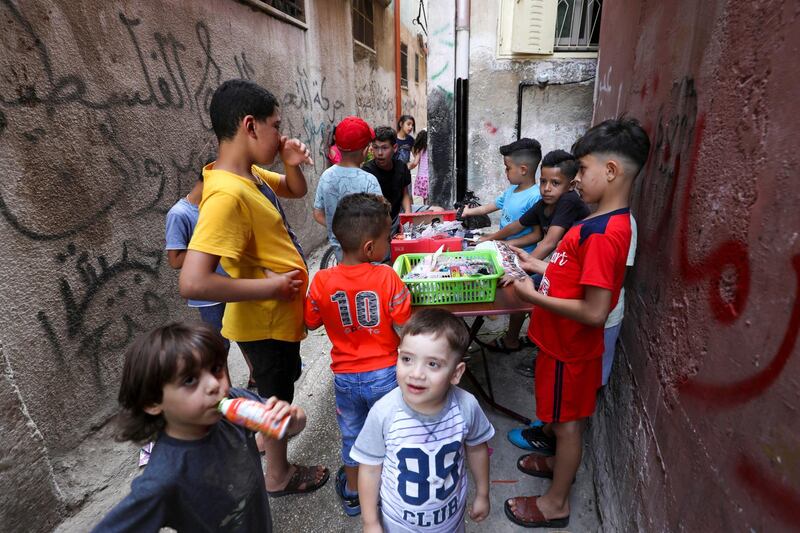 Palestinian children gather around a street vendor in the Amari refugee camp near the West Bank city of Ramallah on July 29, 2020. - A second wave of coronavirus infections sweeping the Israeli-occupied West Bank is fuelling fears of a surge in overcrowded Palestinian refugee camps where social distancing is widely seen as impossible. The Palestinian health ministry's Tuesday update logged more than 10,860 confirmed cases of infection since the start of the pandemic, including more than 75 deaths. (Photo by ABBAS MOMANI / AFP)