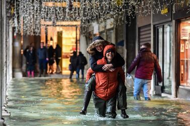 A person carries another across a flooded arcade on November 24, 2019 in Venice during a high tide "Acqua Alta" meteorological phenomenon with a high of 140 cm expected. Flood-hit Venice was bracing for another, though smaller, high tide on November 24, after Italy declared on November 15 a state of emergency for the UNESCO city where perilous deluges have caused millions of euros worth of damage AFP
