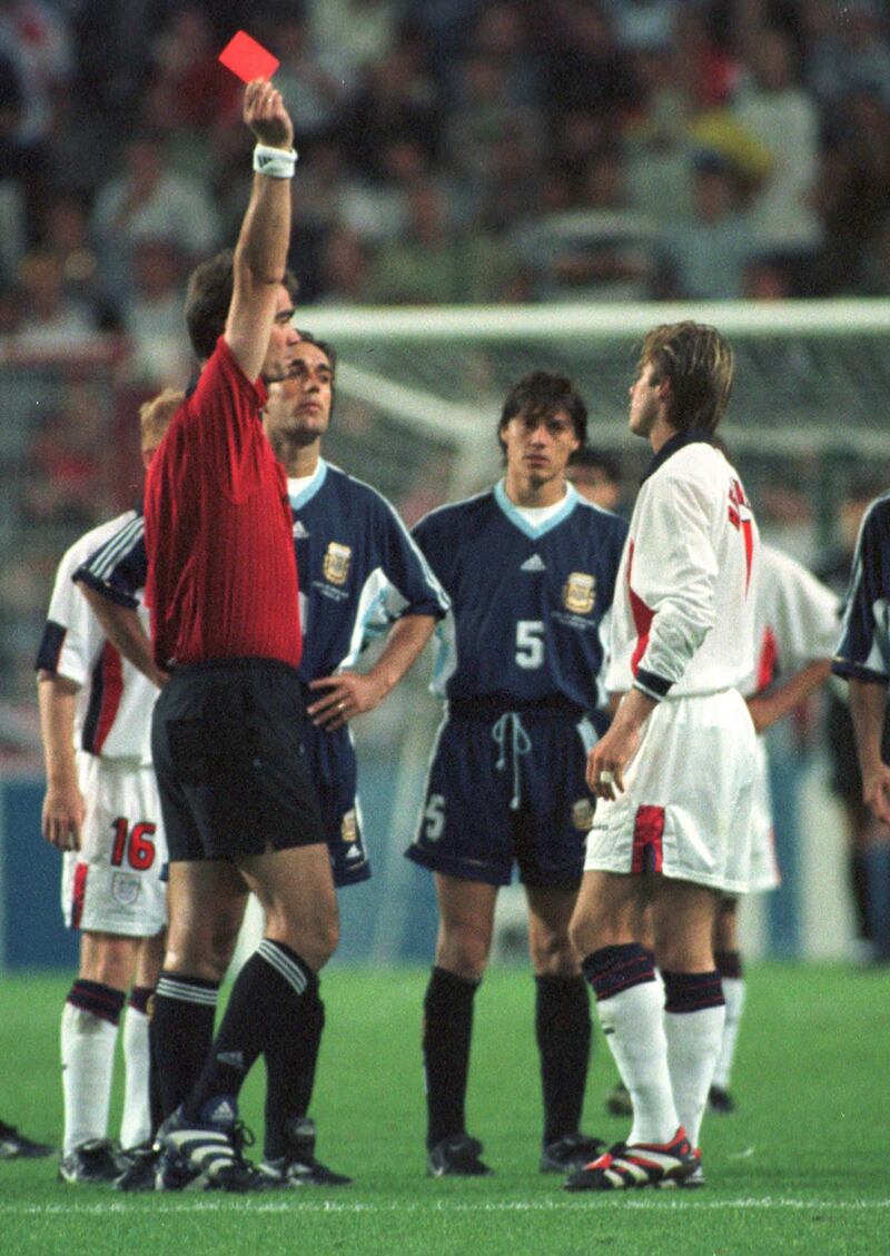 FILE - This is a  June 30, 1998 file photo of England's David Beckham, right,  receiving a red card from  Denmark's referee Kim Milton Nielsen during the England vs Argentina second round World Cup 98, soccer match at  in Saint Etienne France. David Beckham is retiring from soccer after the season, ending a career in which he become a global superstar since starting his career at Manchester United. The 38-year-old Englishman recently won a league title in a fourth country with Paris Saint-Germain. He said in a statement Thursday may 16, 2013 he is "thankful to PSG for giving me the opportunity to continue but I feel now is the right time to finish my career, playing at the highest level." (AP Photo/Denis Doyle, File) *** Local Caption ***  Britain Soccer England Beckham.JPEG-09648.jpg
