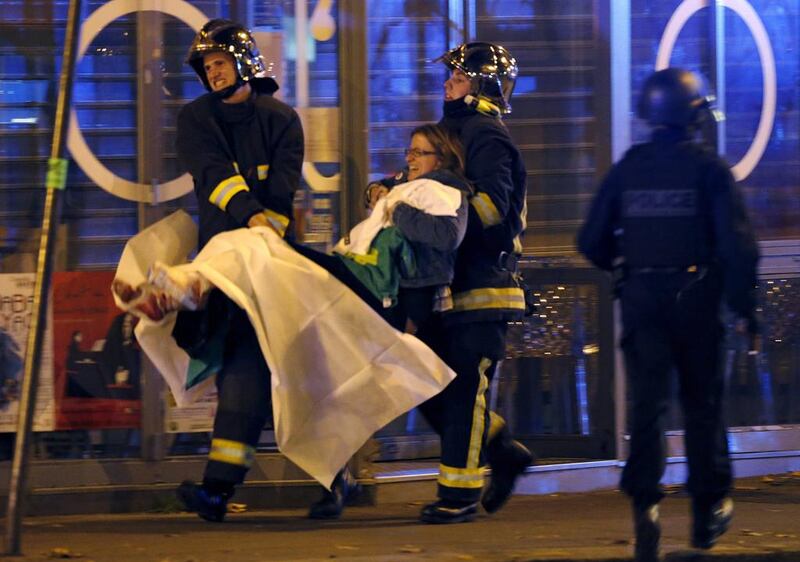 French fire brigade members aid an injured individual near the Bataclan concert hall following fatal shootings in Paris, France, on Friday. Christian Hartmann / Reuters