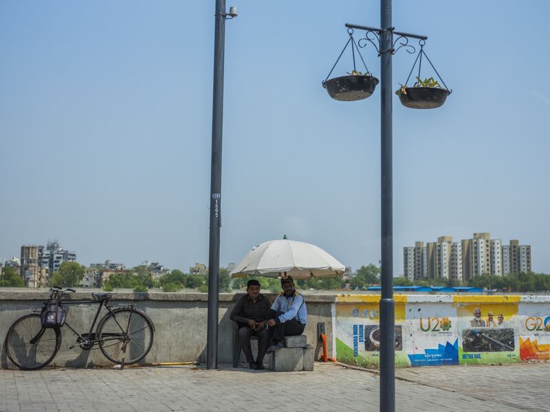 Men shelter under an umbrella in Ahmedabad, one of several Indian cities facing rising temperatures. Bloomberg