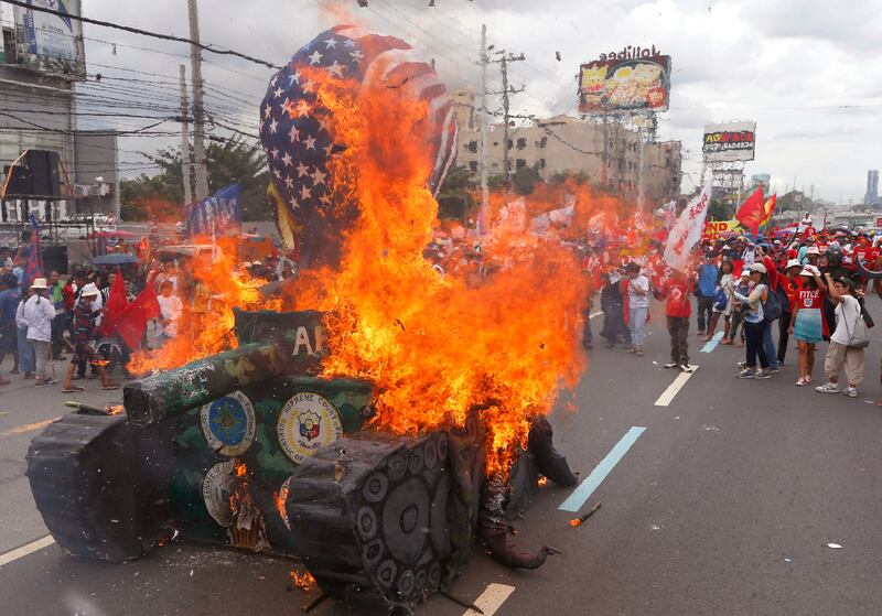 Protesters burn a mock tank that they depict as alleged collusion of Philippines and the United States militaries before marching towards the Lower House with an effigy of president Rodrigo Duterte. Bullit Marquez / AP Photo
