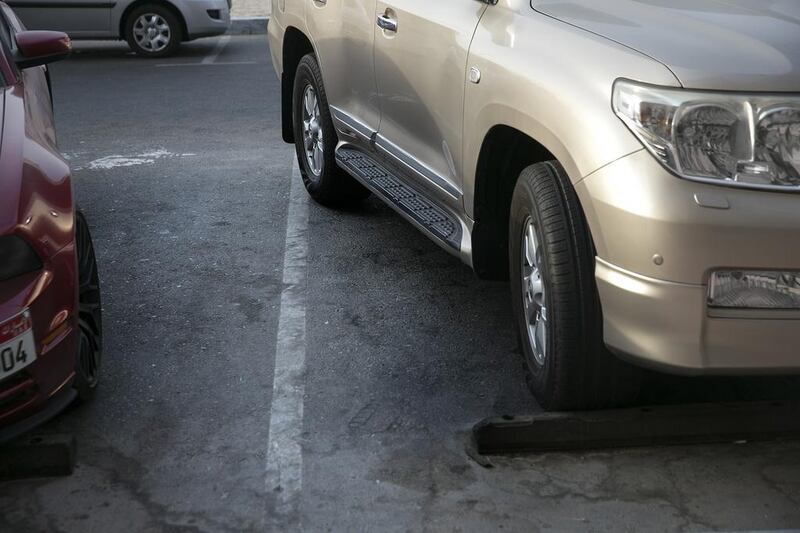 A car stands parked haphazardly, crossing into the next parking spot, near a grocery store in Abu Dhabi.  Silvia Razgova / The National
