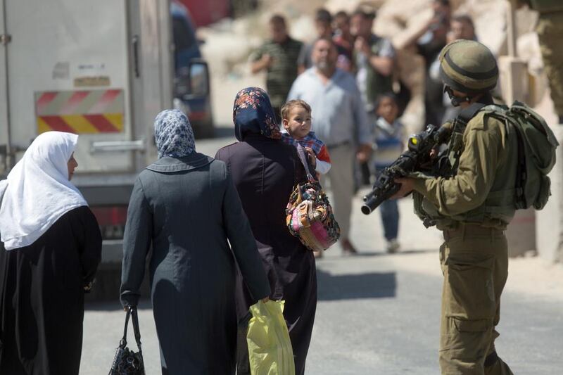 Palestinians walk past an Israeli checkpoint in the West Bank town of Hebron. Menahem Kahana / AFP