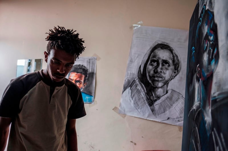 Eritrean artist Nebay Abraha, 23, walks past his paintings hung on the wall of his room and studio in Addis Ababa. AFP