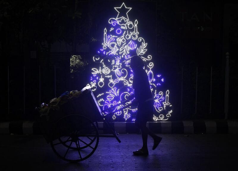 A municipal worker pushes a garbage cart past a Christmas decoration installed on a pavement fence in Kolkata, India.  Rupak De Chowdhuri / Reuters