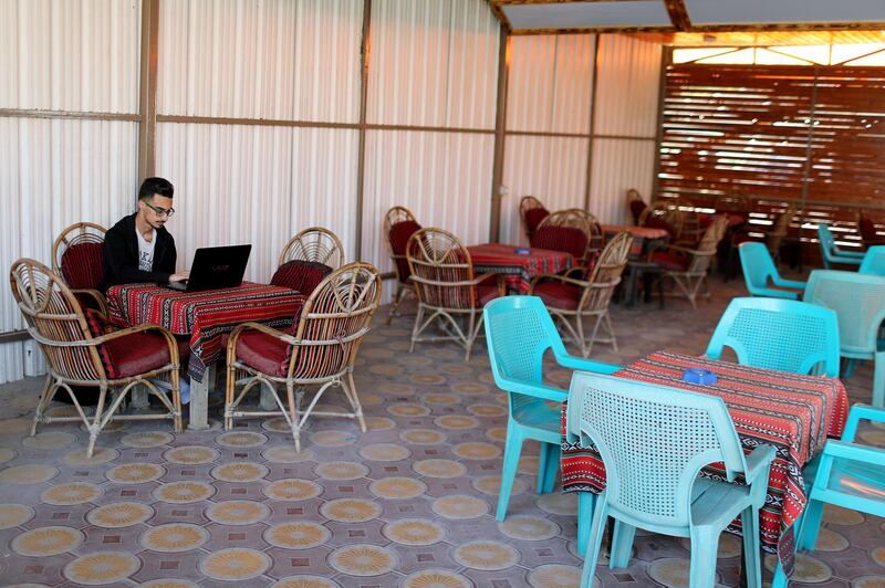 A Palestinian graduate uses his laptop as he sits in a coffee shop amid the coronavirus crisis, in Gaza City. Reuters