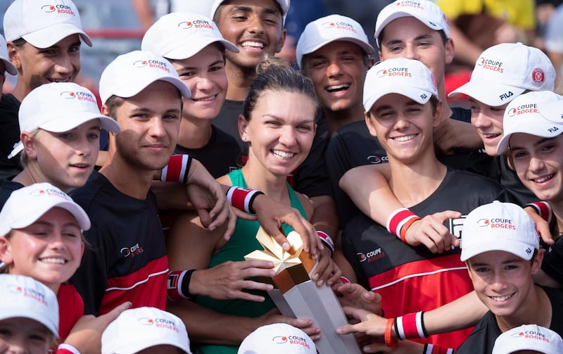 Simona Halep, center, of Romania, poses with her trophy and the ball crew after defeating Sloane Stephens, of the United States, in the final of the Rogers Cup women's tennis tournament Sunday, Aug. 12, 2018, in Montreal. (Paul Chiasson/The Canadian Press via AP)