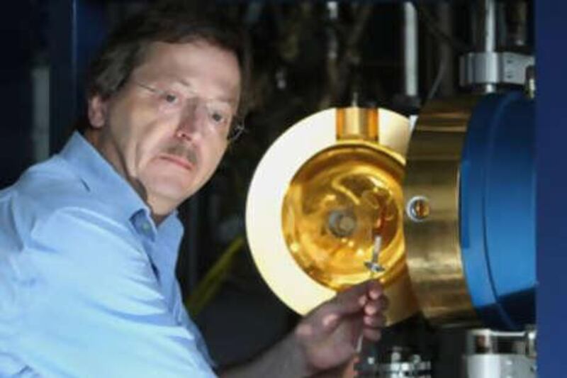 Armin Reller holds a synthetic ruby while sitting in front of a floating zone furnace, an oven used for growing crystals.