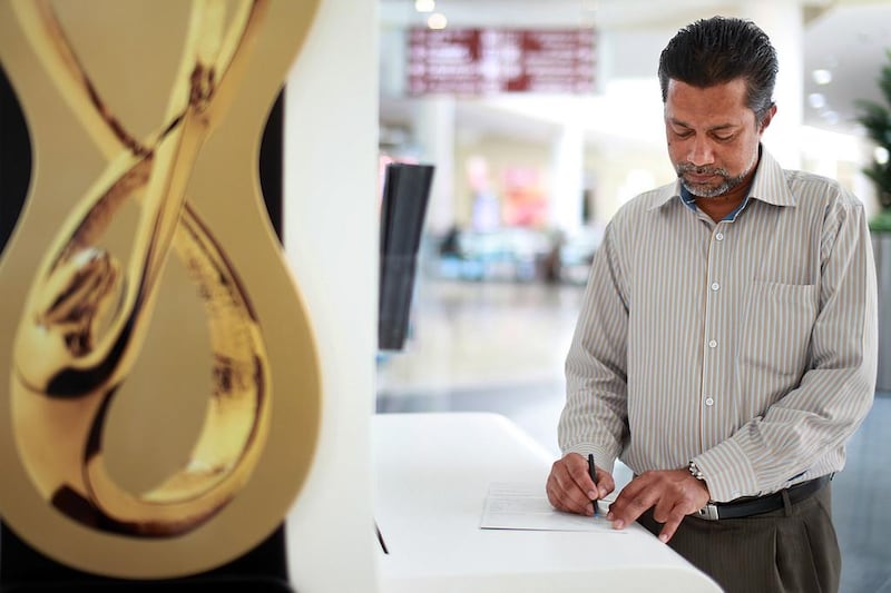 A man fills out a form for the Abu Dhabi Awards at a booth in Al Wahda mall in Abu Dhabi. Delores Johnson / The National