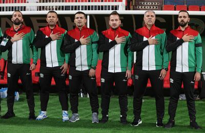 Palestine manager Makram Daboub, second right, and his coaching staff during the national anthems ahead of the game against Lebanon in Sharjah. EPA