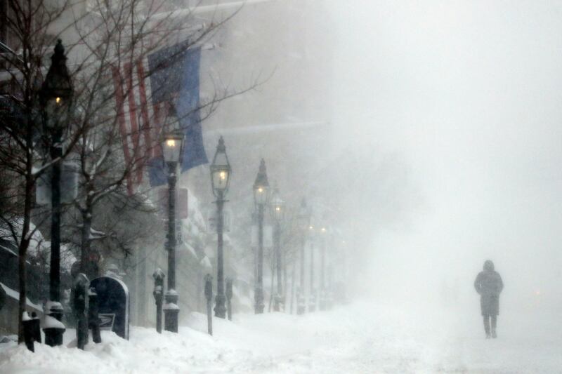A person walks on Beacon Street during heavy snow, in Boston.  AP
