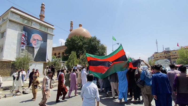 Afghans pass by a poster of President Ashraf Ghani, who has fled the country. EPA