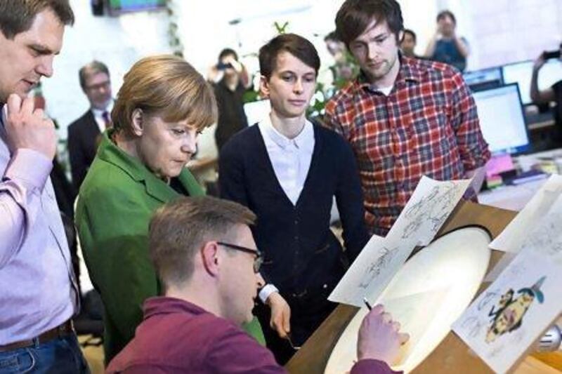 Angela Merkel watches an artist during a tour of local start-ups in Berlin. The German capital is gaining a reputation as a technology hub. Thomas Peter / AFP