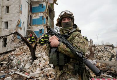 A Ukrainian soldier stands against the background of an apartment house ruined in the Russian shelling in Borodyanka, Ukraine, Wednesday, Apr.  6, 2022.  (AP Photo / Efrem Lukatsky)