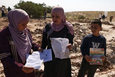 Palestinians pick up papers and books from the site of a school that was demolished by the Israeli authorities who said it was built without permission in the village of Jabbet al-Dhib, east of Bethlehem in the occupied West Bank, on May 7, 2023.  (Photo by HAZEM BADER  /  AFP)