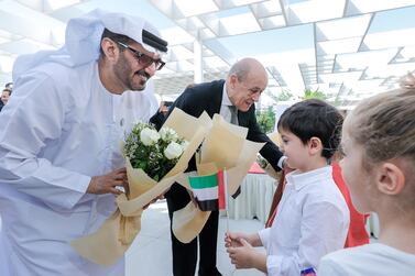 Mr Le Drian and Hussain Ibrahim Al Hammadi, the Minister of Education, , are given flowers by the primary school pupils. Victor Besa / The National