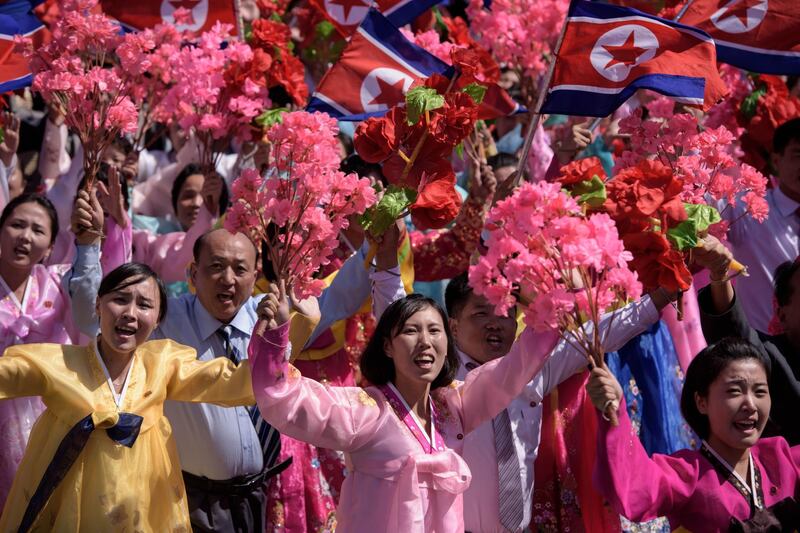 Participants wave flowers as they march past a balcony from where North Korea's leader Kim Jong Un was watching, during a mass rally on Kim Il Sung square in Pyongyang. AFP