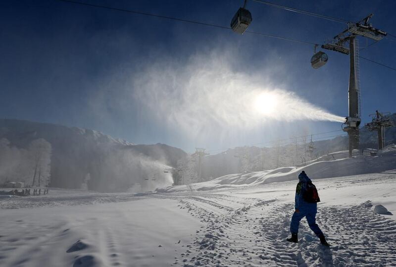 A volunteer walks toward a snow cannon near Extreme Park which will be the venue for the freestyle skiing and snowboarding disciplines at the Sochi 2014 Winter Olympics. Luca Bruno / AP